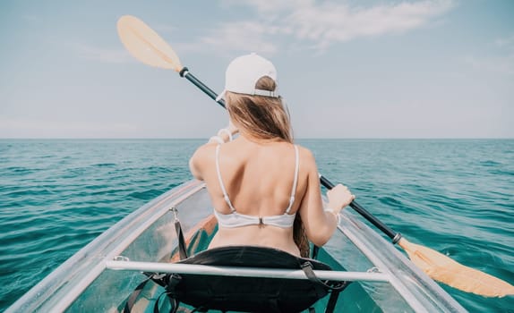 Woman in kayak back view. Happy young woman with long hair floating in transparent kayak on the crystal clear sea. Summer holiday vacation and cheerful female people having fun on the boat.