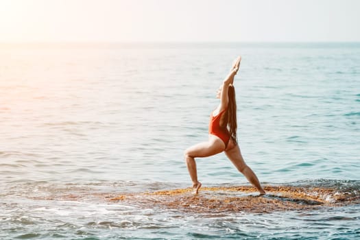 Woman sea yoga. Back view of free calm happy satisfied woman with long hair standing on top rock with yoga position against of sky by the sea. Healthy lifestyle outdoors in nature, fitness concept.