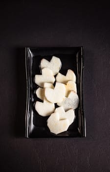 sliced ingredients in a flat black plate on a white background