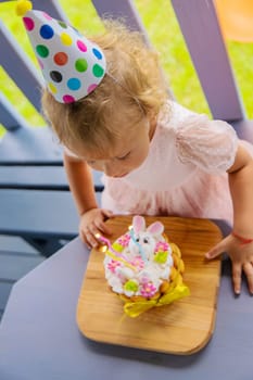 A three year old child blows candles on a cake. Selective focus. Kid.