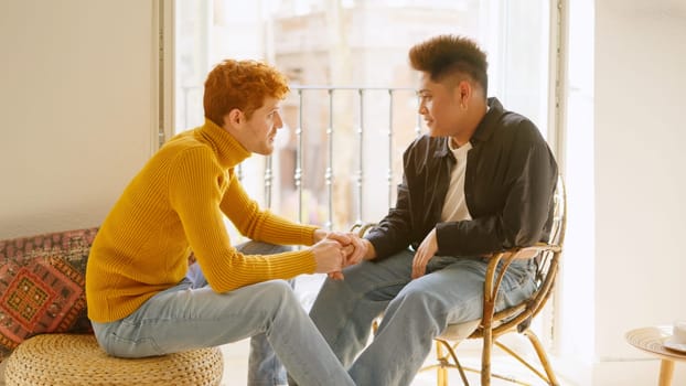 Gay man takes his partner's hand to communicate something to him.