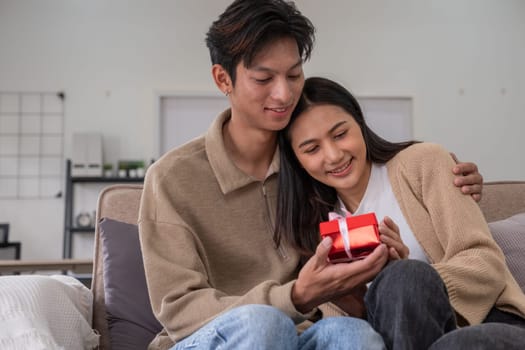 Asian couple affectionately hugging their lover, giving gifts, giving a surprise on Valentine's Day. home interior decoration.