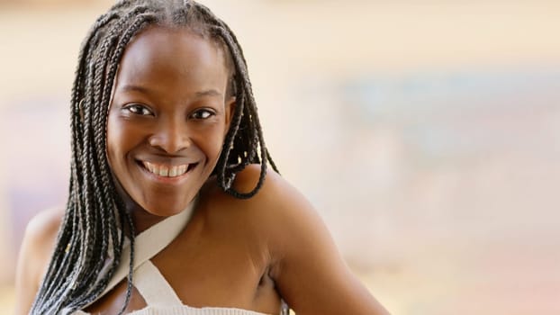 African and young woman smiling at the camera from a balcony, with copy space