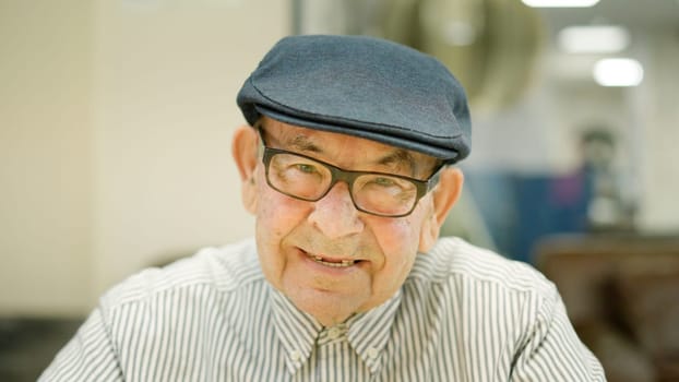 Close-up picture of a senior man with beret smiling at camera in a nursing home