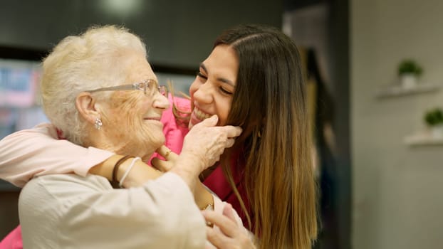Photo of caregiver and senior woman looking at each other smiling in geriatrics