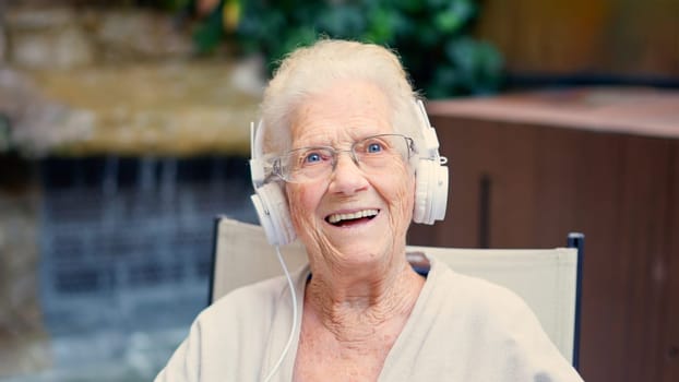 Photo of a female senior podcaster and influencer waving at camera from a nursing home
