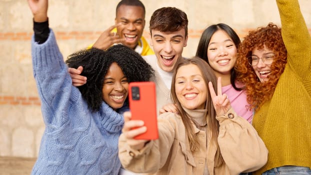 Diverse teenager people taking a selfie celebrating something very happy, smiling and laughing outdoors