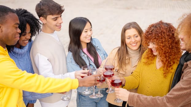 Multicultural young people toasting with wine in the street