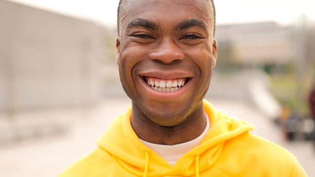 An african young man standing outdoors and laughing. Close up