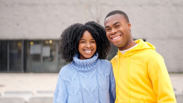 African young couple smiling at camera standing in the street