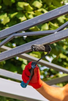 A man paints metal poles. Selective focus. Hand.