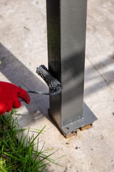 A man paints metal poles. Selective focus. Hand.