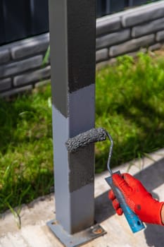 A man paints metal poles. Selective focus. Hand.