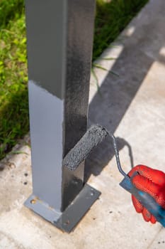 A man paints metal poles. Selective focus. Hand.