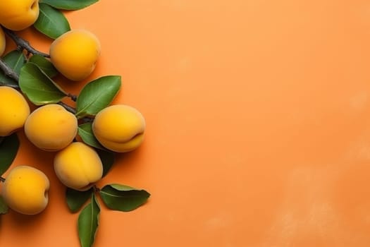 Fresh yellow apricots on an orange background with leaves attached.