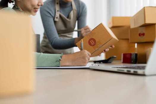 Asian woman write parcel box to prepare for delivery to customer. e-business concept.