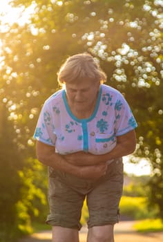 An old woman has a stomach ache. Selective focus. Nature.