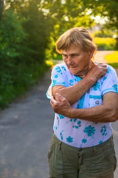 Old woman arm hurts, elbow. Selective focus. Nature.