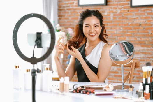 Asian Woman influencer shoot live streaming vlog video review makeup uttermost social media or blog. Happy young girl with cosmetics studio lighting for marketing recording session broadcasting online