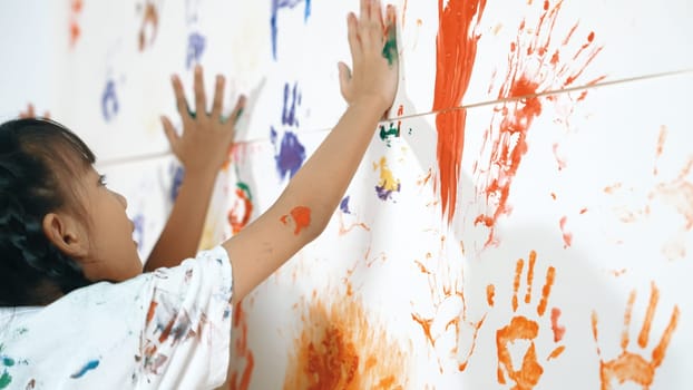 Close up of colorful stained wall was painted by student in art class. Funny asian girl playing with colorful watercolor with diverse children at messy room. Creative activity concept. Erudition.