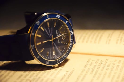 Beautiful gold men's watch with a black strap on a wooden stand, on a gray background. Beautiful gold watch. A luxury brand watch