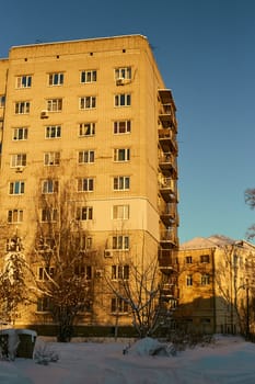 Vertical photo of a multi-storey brick house in winter against the background of a blue sky. Construction and renovation.