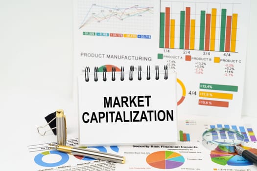 Business concept. On the table are reports with graphs and a notepad with the inscription - Market capitalization