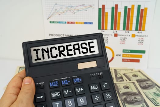 Business concept. On the table there are financial reports, dollars, in the hands of a calculator with the inscription - INCREASE