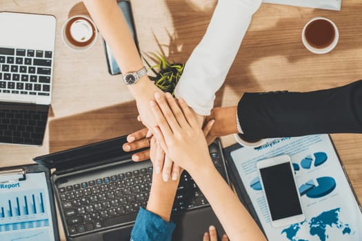 Businessmen and businesswomen joining hands in group meeting at multicultural office room showing teamwork, support and unity in business. Diversity workplace and corporate people working concept. uds