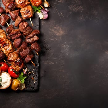 Assorted delicious grilled meat with vegetables on a slate plate.