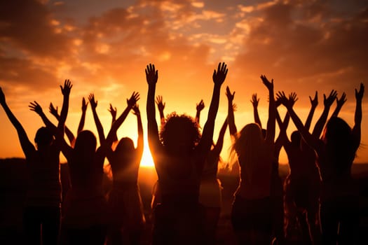 Silhouettes of many women with their hands raised up at sunset. Women's unity concept.