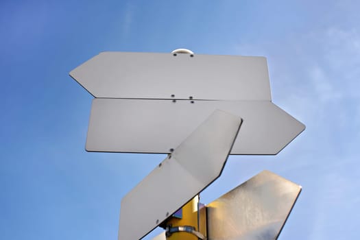 Empty metal tables shaped like arrows against blue sky - add your text