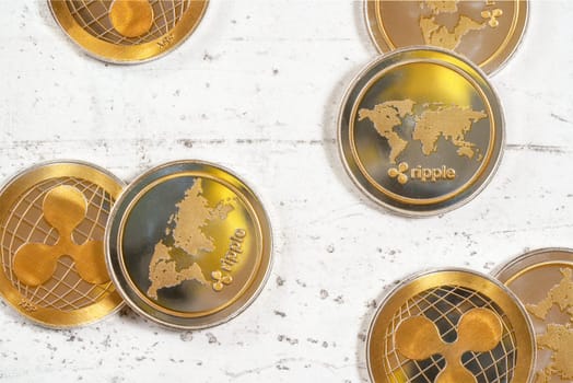 Top down view, golden XRP cryptocurrency -  ripple coins on white stone board