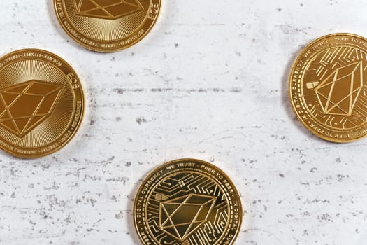 Golden commemorative EOS - EOSIO  cryptocurrency - coins on white stone board, flat lay view