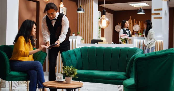 Asian woman paying for coffee and giving tip to waiter, feeling pleased with customer services and offering cash. Traveler using credit card payment at pos terminal, enjoy refreshment.