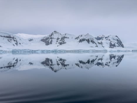 A huge high breakaway glacier in the southern ocean off the coast of Antarctica, the Antarctic Peninsula, the Southern Arctic Circle, azure water, cloudy weather. High quality photo