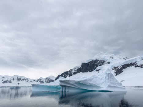 A huge high breakaway glacier in the southern ocean off the coast of Antarctica, the Antarctic Peninsula, the Southern Arctic Circle, azure water, cloudy weather. High quality photo