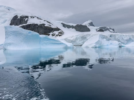 A huge high breakaway glacier in the southern ocean off the coast of Antarctica, the Antarctic Peninsula, the Southern Arctic Circle, azure water, cloudy weather. High quality photo