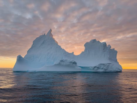 A huge high breakaway glacier drifts in the southern ocean off the coast of Antarctica at sunset, the Antarctic Peninsula, the Southern Arctic Circle, azure water, cloudy weather. High quality photo