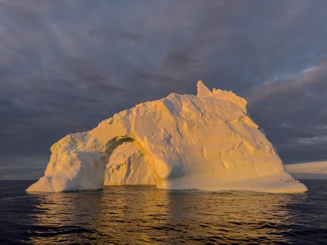 A huge high breakaway glacier drifts in the southern ocean off the coast of Antarctica at sunset, the Antarctic Peninsula, the Southern Arctic Circle, azure water, cloudy weather. High quality photo