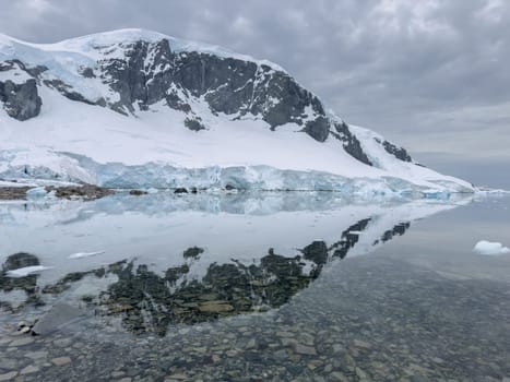 A huge high breakaway glacier in the southern ocean off the coast of Antarctica, the Antarctic Peninsula, the Southern Arctic Circle, azure water, cloudy weather. High quality photo