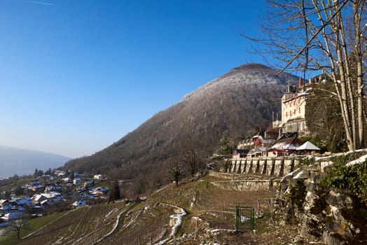 Snowy Castle on a Hill near Annecy, France. Winter Wonderland with Snow-Covered Rooftops. Experience the enchantment of a winter landscape with this captivating image showcasing a castle perched on a hill near Annecy, France. The scene is adorned with snow, creating a picturesque winter wonderland, while below, charming houses with snow-covered rooftops add to the magical ambiance.