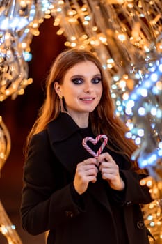 Christmas mood. Woman with long hair in sity decorated for Christmas. She is dressed in a black coat