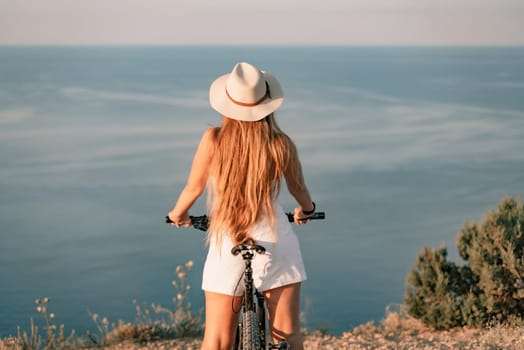 A woman cyclist on a mountain bike looking at the landscape sea. Adventure travel on bike