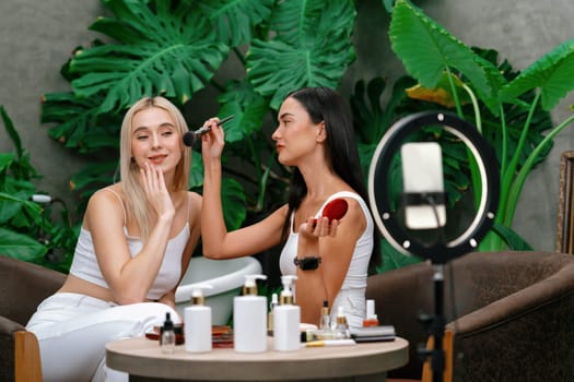 Two beautiful content creator making natural beauty and cosmetic tutorial on green plant garden video. Beauty blogger showing how to beauty care to social medial audience using selfie stick . Blithe