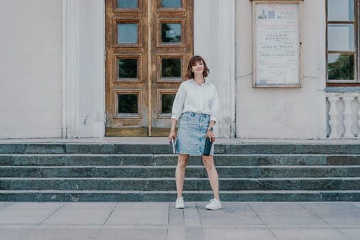 Woman staircase city. A business woman in a white shirt and denim skirt walks down the steps of an ancient building in the city.