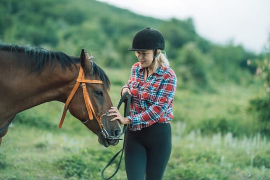 Happy blonde with horse in forest. Woman and a horse walking through the field during the day. Dressed in a plaid shirt and black leggings