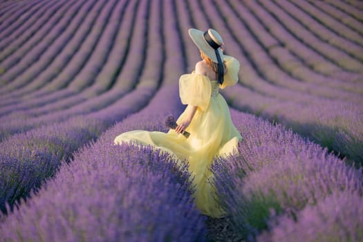 Back view woman lavender sunset. Happy woman in yellow dress holds lavender bouquet. Aromatherapy concept, lavender oil, photo session in lavender.