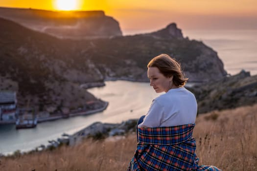 Happy woman on sunset in mountains. Woman siting with her back on the sunset in nature in summer. Silhouette