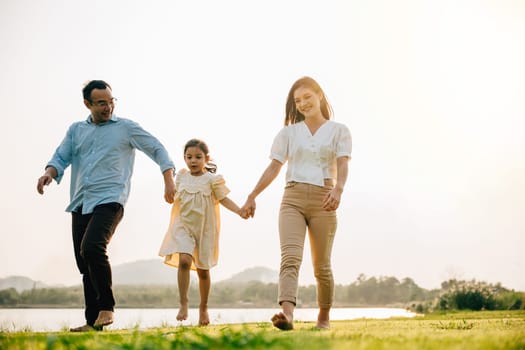 Father and mother with daughter walking together and smiling in a beautiful park on a sunny day, feeling the togetherness and the beauty of the outdoors, Happy family day